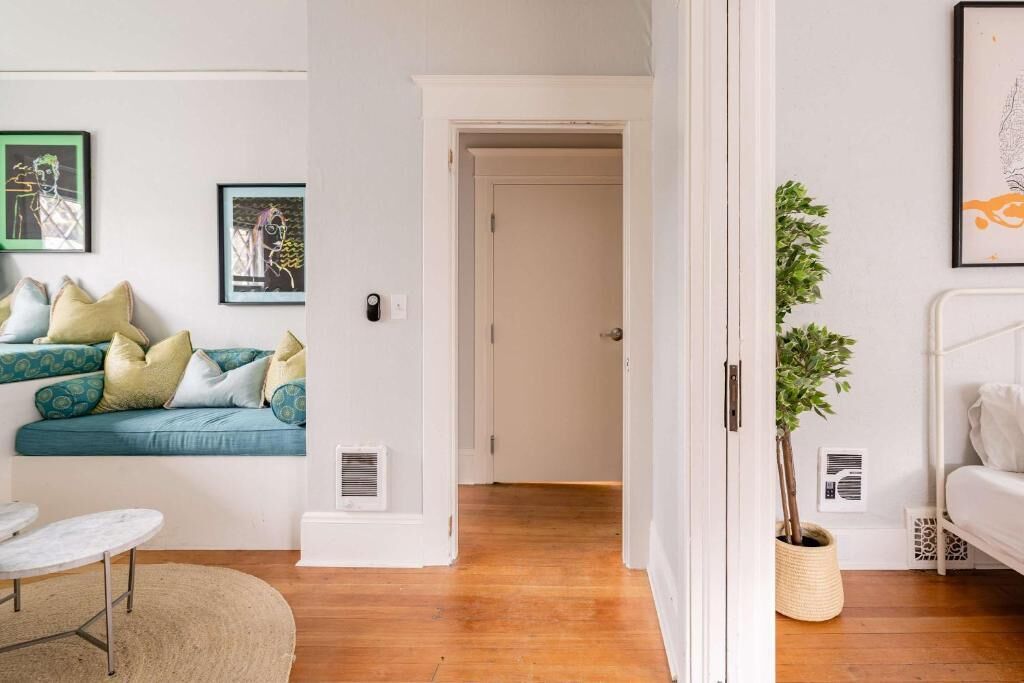 Una habitación con sofá, una mesita, una planta en maceta y una cama.