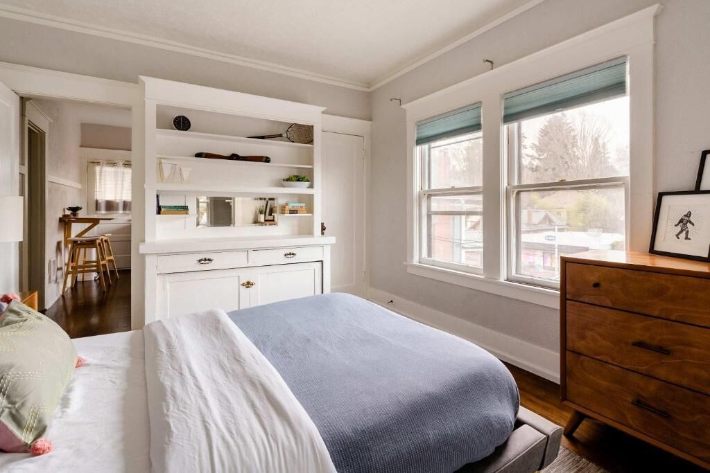 A bedroom with a bed, a dresser, a desk, and a window.