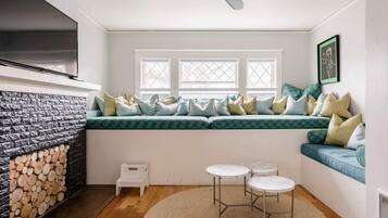 Une piÚce chaleureuse avec un banc intégré, une cheminée, un ventilateur de plafond et une petite table avec des chaises.