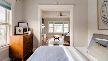 Un dormitorio con cama, cómoda y vista a otra habitación.