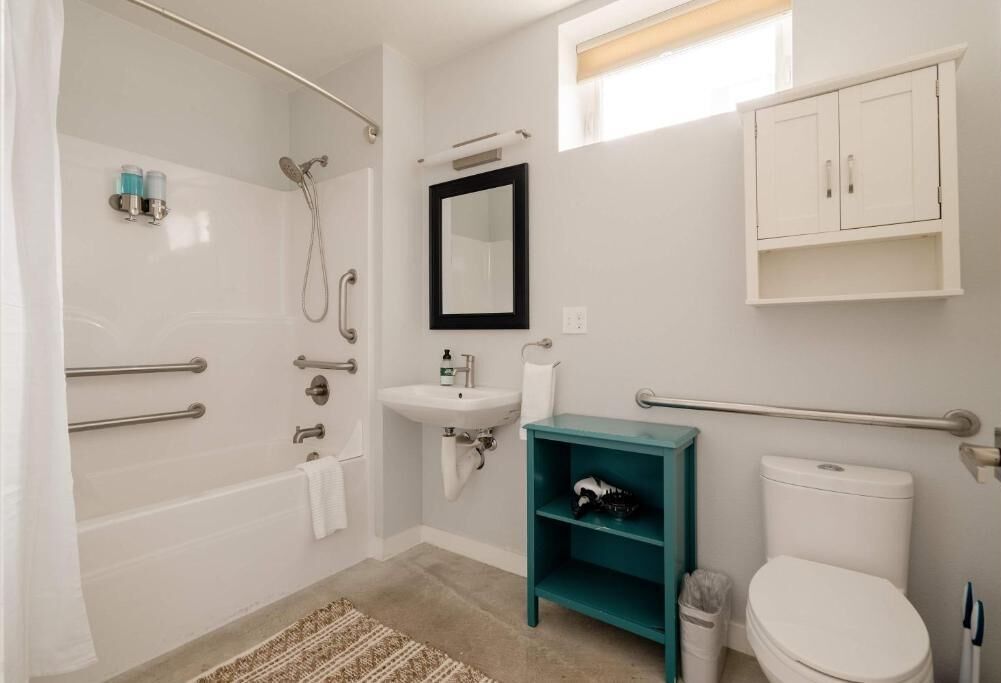 Une salle de bain équipée d’une douche, d’un lavabo, de toilettes et d’une étagère de couleur turquoise.