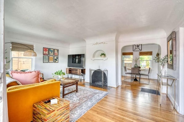 A living room with a sofa, TV, fireplace, and dining area.