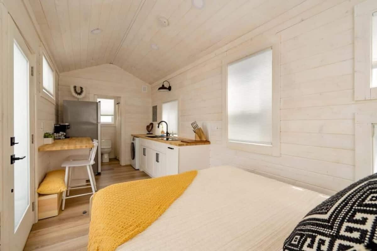 Una habitación compacta con cama, una kitchenette pequeña, zona de comedor y ventana.