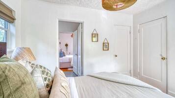 A bedroom with a bed, a door, and a window.