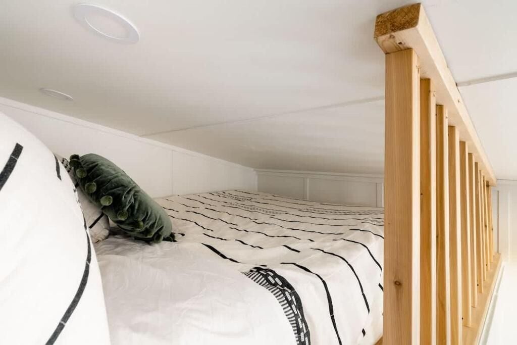 A bunk bed with a striped bedspread, a green pillow, and a wooden headboard.