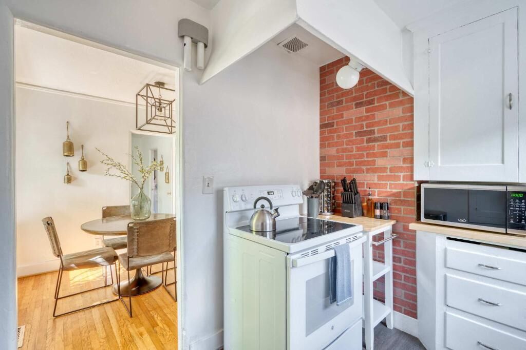Une cuisine de taille réduite avec un fourneau blanc, un four à micro-ondes et un mur décoratif en briques.