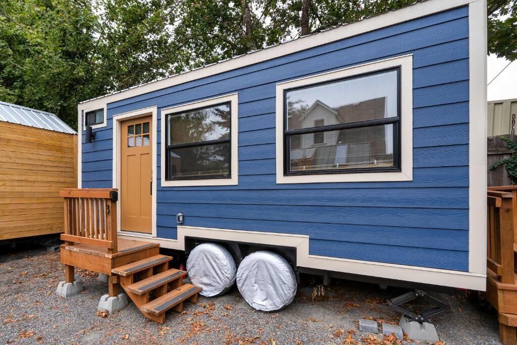 A mobile home with a front porch, two windows, and a sliding door.