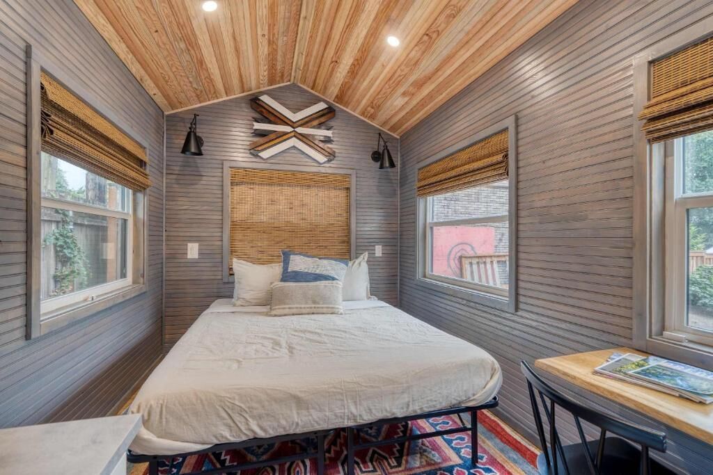 A bedroom with a bed, a table, and a window.