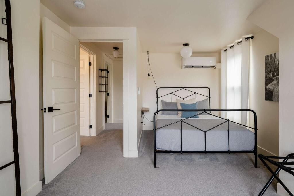 Une chambre à coucher avec un lit, une porte, un couloir et un appareil de climatisation.