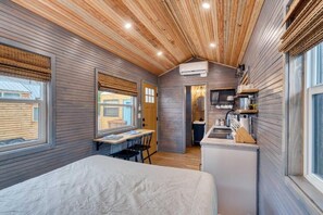 A compact room with a bed, a desk, and a kitchenette.