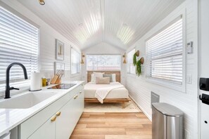 Ein gemütliches Schlafzimmer mit Bett, Nachttisch und einem Fenster mit Jalousien.