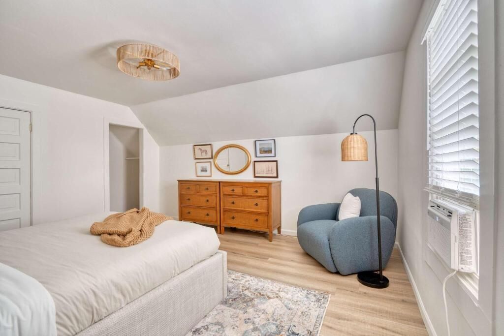 A bedroom with a bed, dresser, chair, and a ceiling light fixture.
