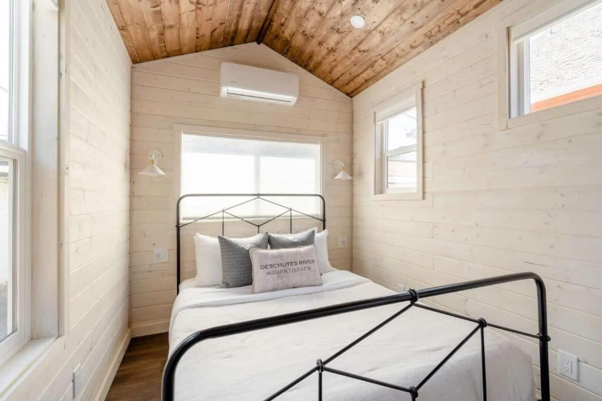 A bedroom with a bed, wooden walls, a sloped ceiling, and a window.