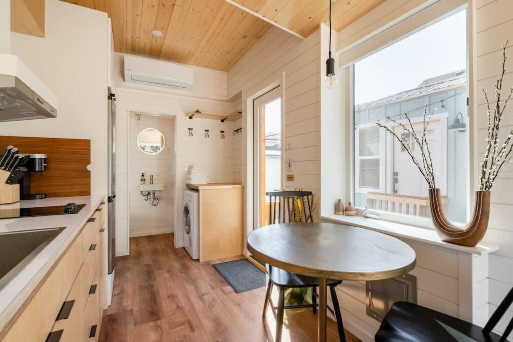 Une cuisine moderne avec un plancher en bois, un coin repas avec une table ronde et une vue par la fenêtre.