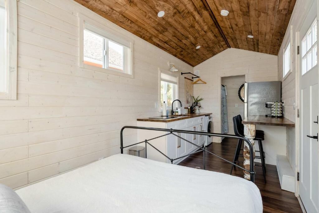 A bedroom with a bed, a kitchenette with a sink, and a dining area with a table and chairs.