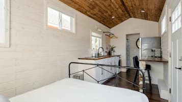 A bedroom with a bed, a kitchenette with a sink, and a dining area with a table and chairs.