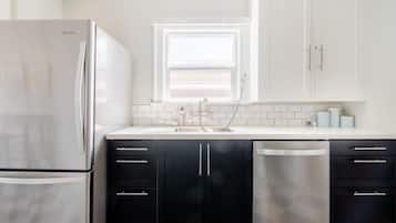 Una cocina con un refrigerador de acero inoxidable, lavavajillas y gabinetes negros.