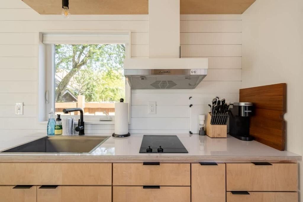 A modern kitchen with a sink, stove, and coffee maker.