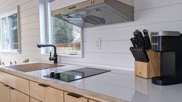 A modern kitchen with a stainless steel sink, a built-in knife block, and a coffee maker.