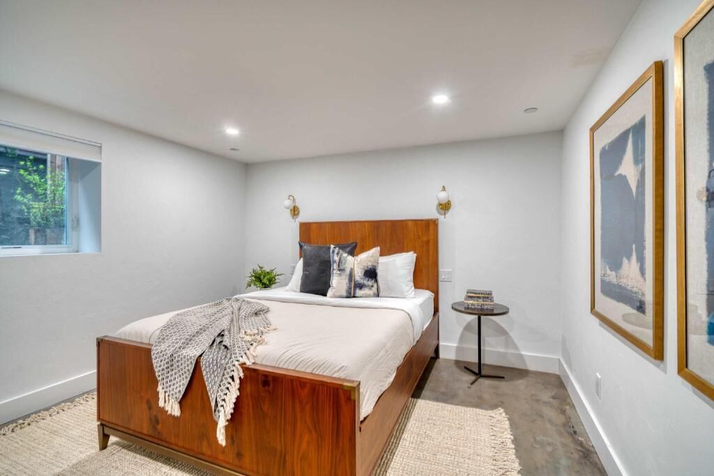 Een slaapkamer met een houten bed, een klein nachtkastje en een raam.