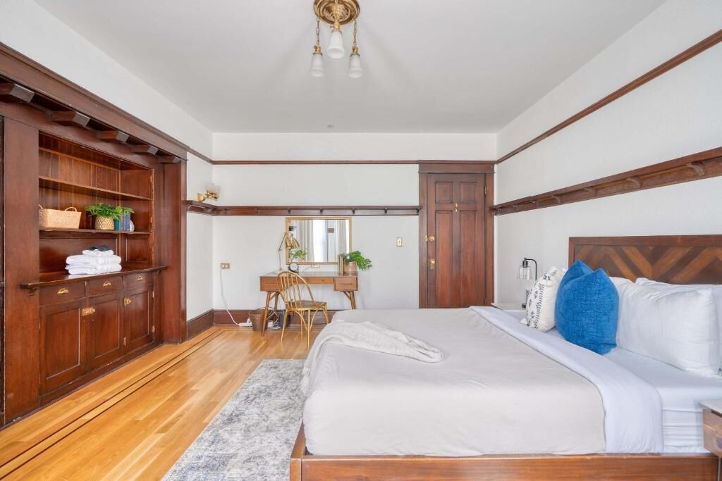 A bedroom with a wooden bed, a desk, and a wardrobe.