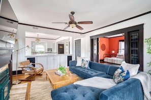 A living room with a blue sofa, a wooden coffee table, and a ceiling fan. - Everett St Stay (Portland)