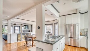 Uma cozinha moderna com armários brancos, eletrodomésticos de aço inoxidável e piso de madeira.