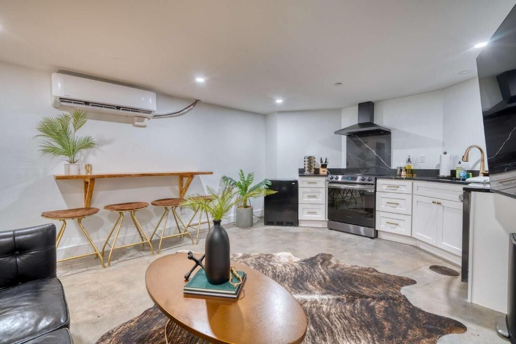 A modern kitchen with white cabinets, a black stove, and a wooden dining table with chairs.