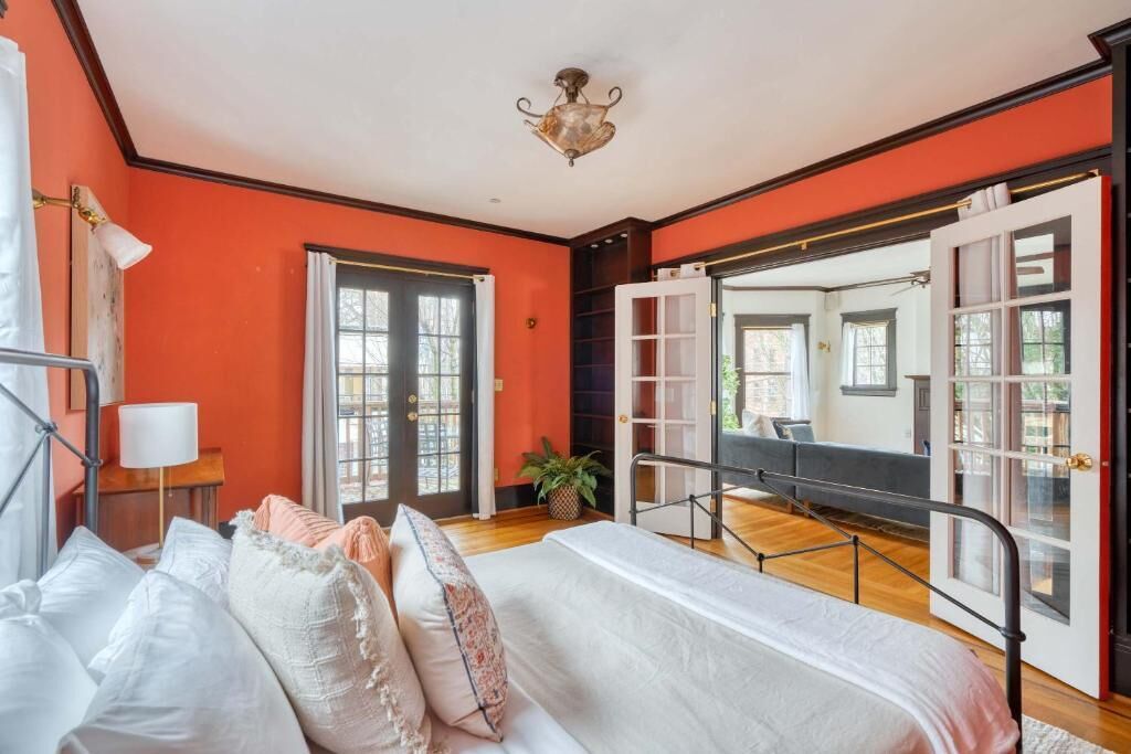 Une chambre à coucher avec un lit, une table de chevet, une lampe, une plante en pot et un grand miroir.