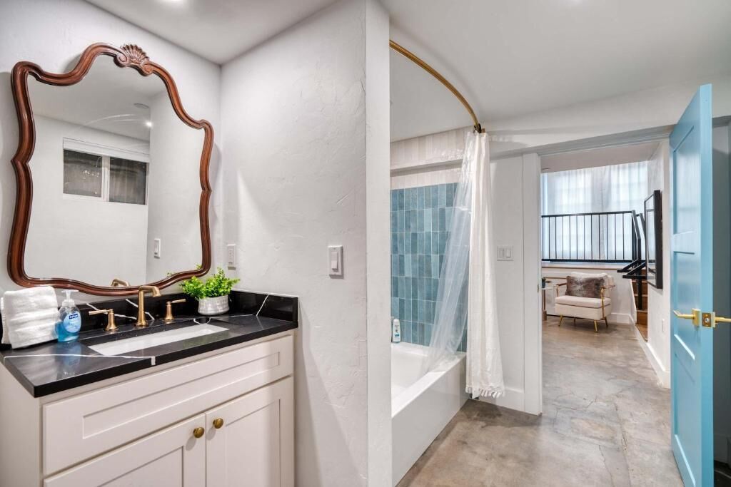 A bathroom with a large mirror, a sink, and a shower area.