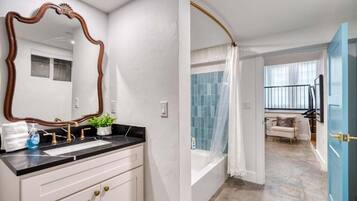 A bathroom with a large mirror, a sink, and a shower area.