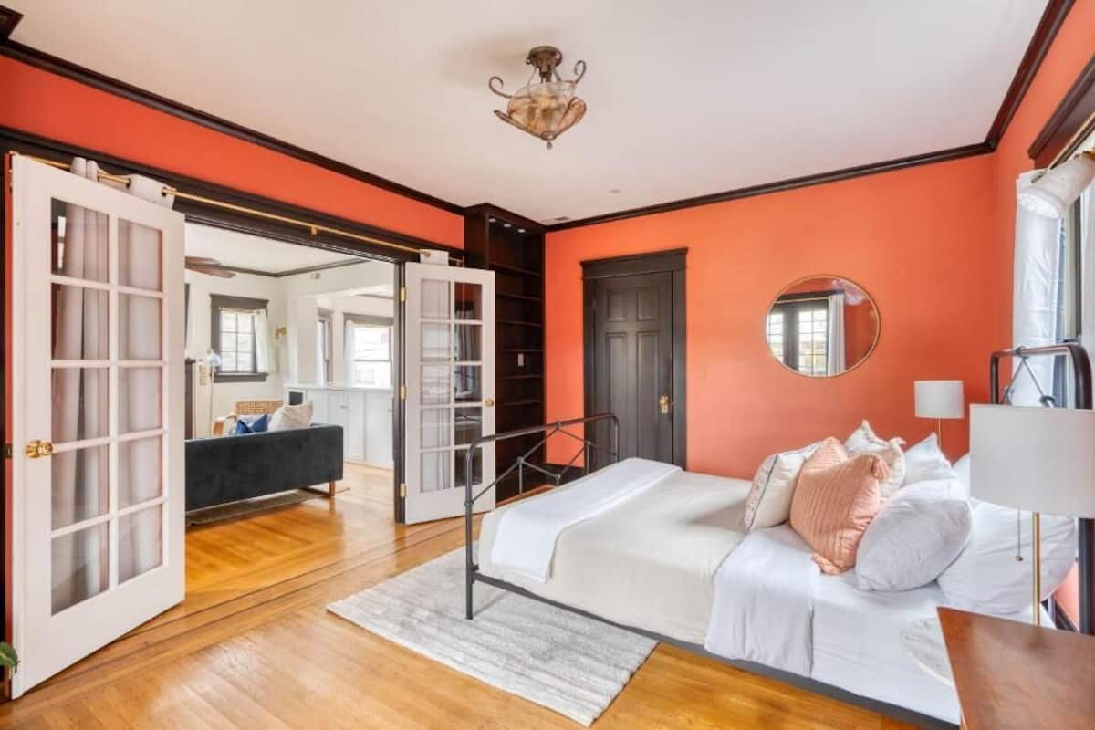 A bedroom with a bed, a bedside table, a mirror, and a wardrobe.