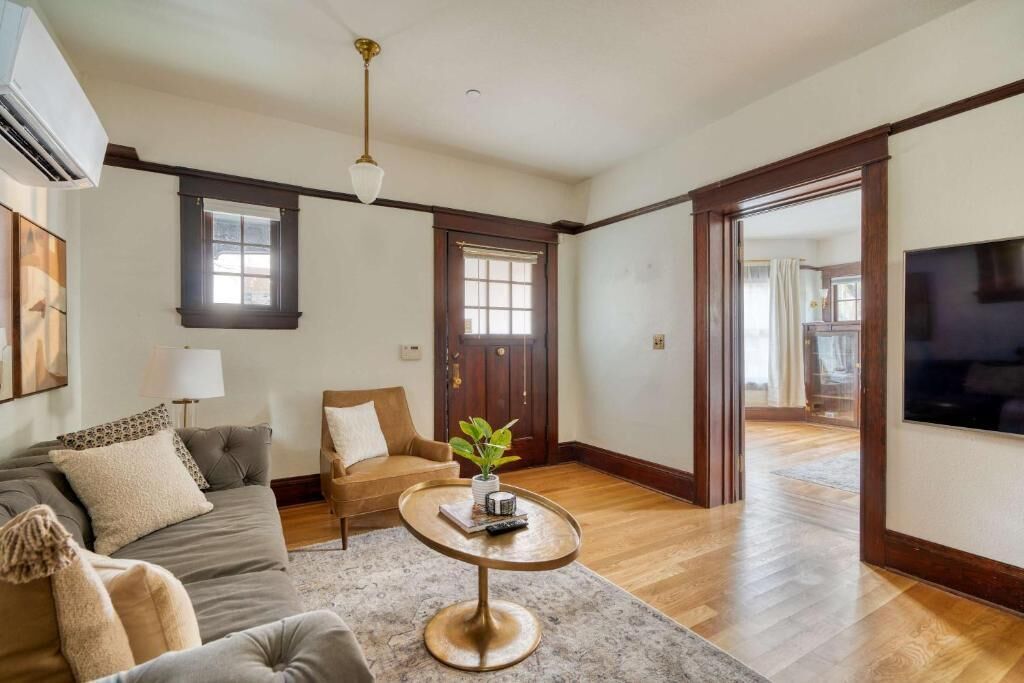 A living room with a sofa, a round coffee table, a plant, and a television.