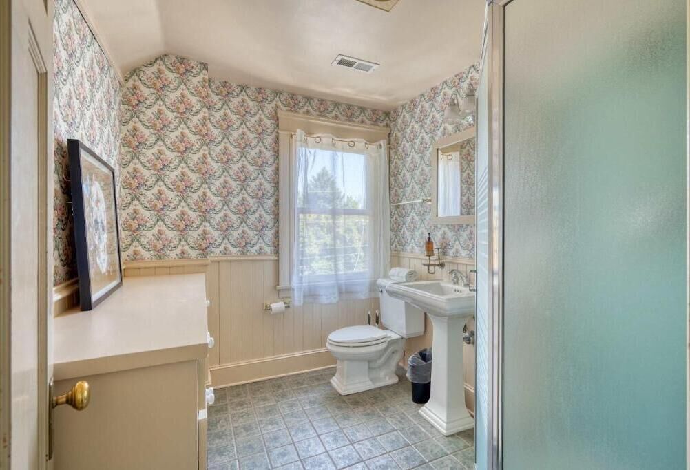 A bathroom with a toilet, sink, and window.