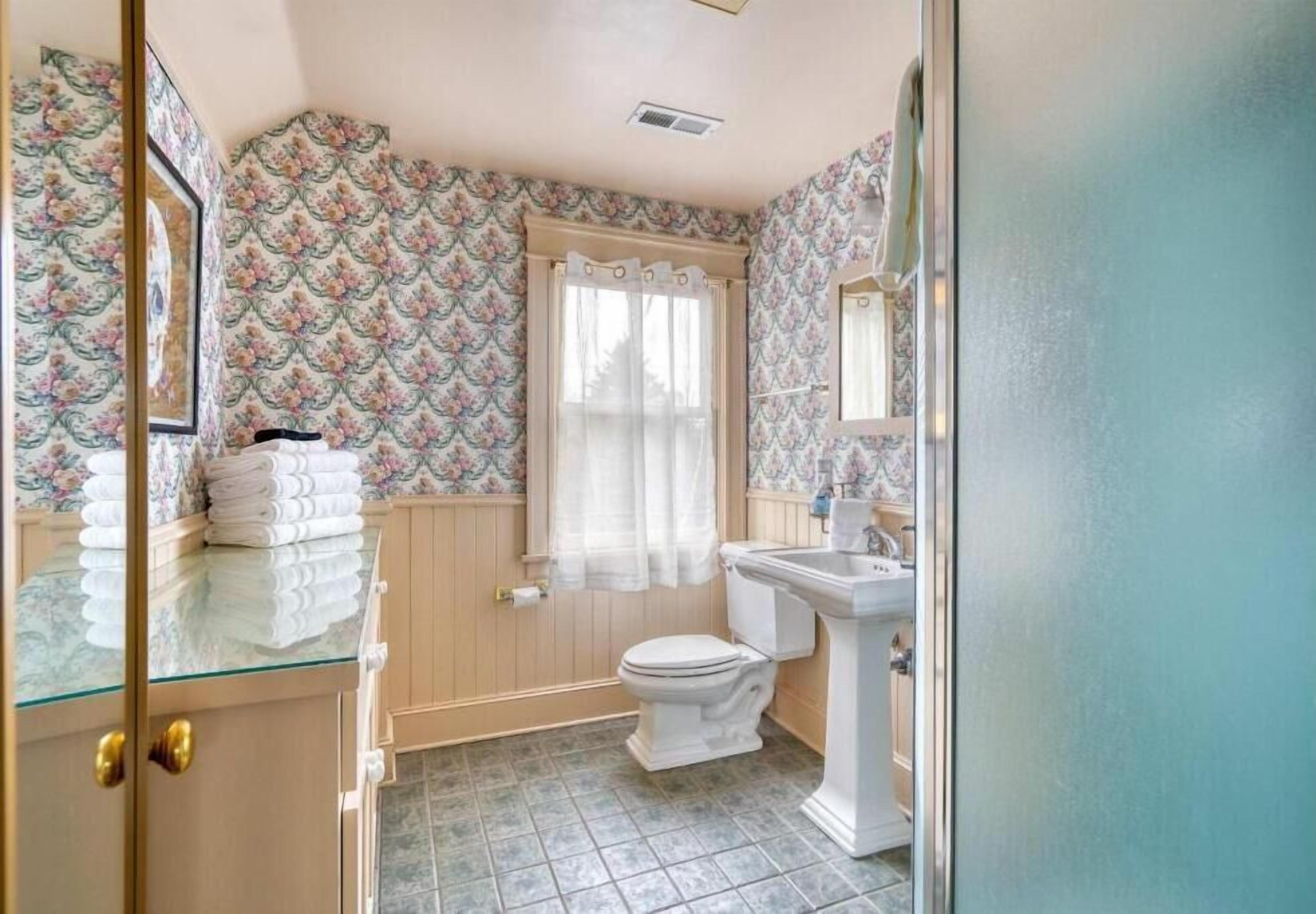 Ein Badezimmer mit Toilette, Waschbecken und einer Glastür zum Raum.
