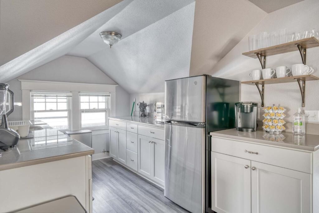 A modern kitchen with white cabinetry, a stainless steel refrigerator, and a coffee maker.