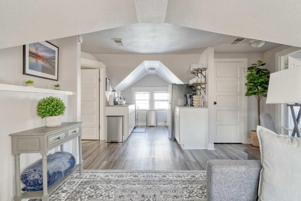 A modern kitchen with white cabinets, a central island, and a view to the dining area.