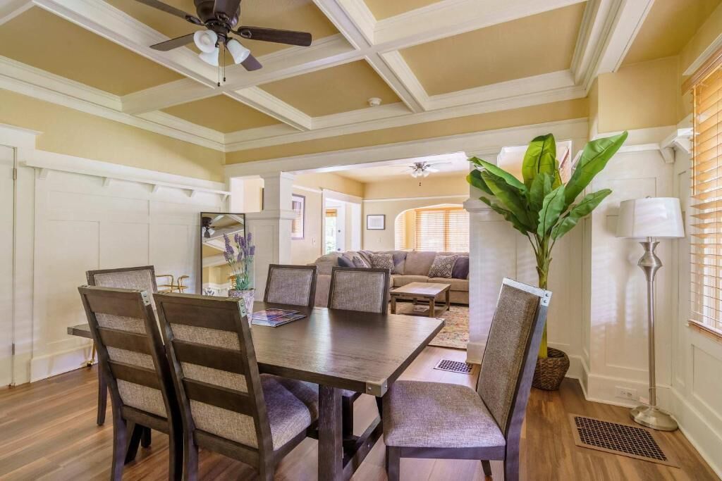 A dining area with a table and chairs, a ceiling fan, a plant, and a lamp.