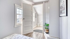 Un dormitorio con cama, puerta que da a un balcón y un cuadro en la pared.