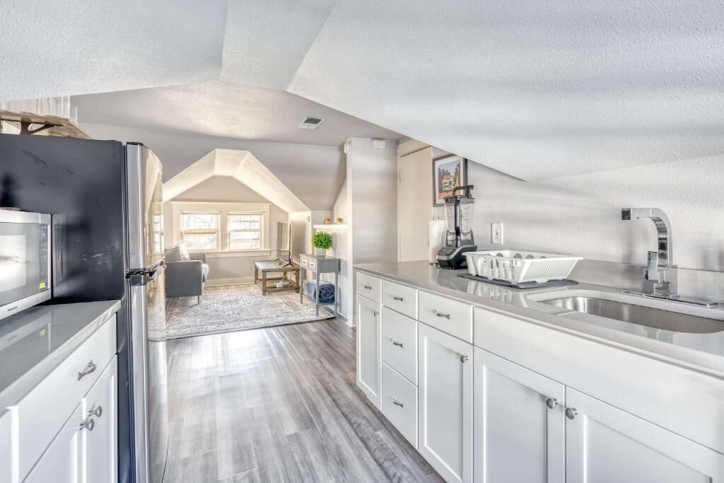 A modern kitchen with stainless steel appliances, a large island with a sink, and a dining area with a table and chairs.