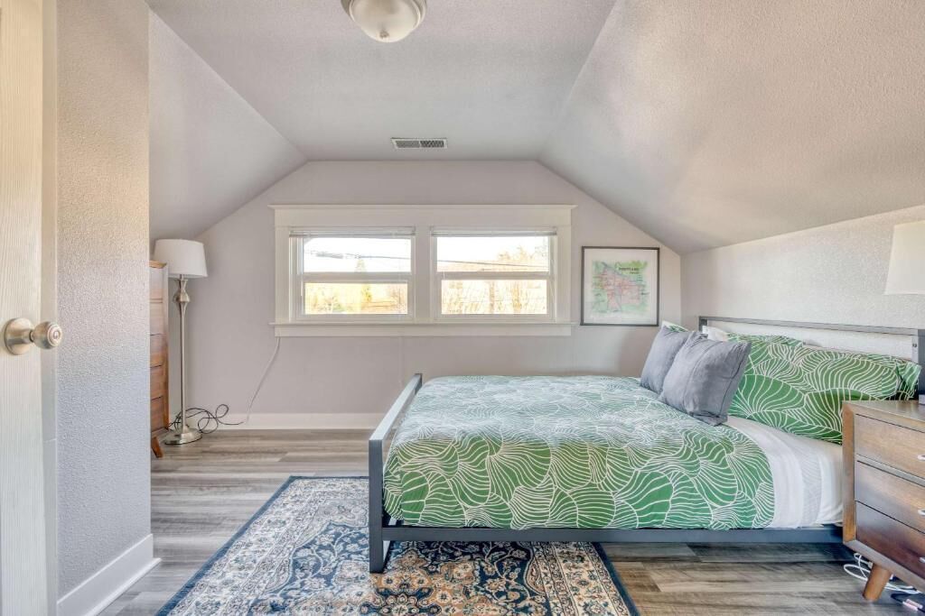 A bedroom with a bed, a window, a lamp, and a rug.