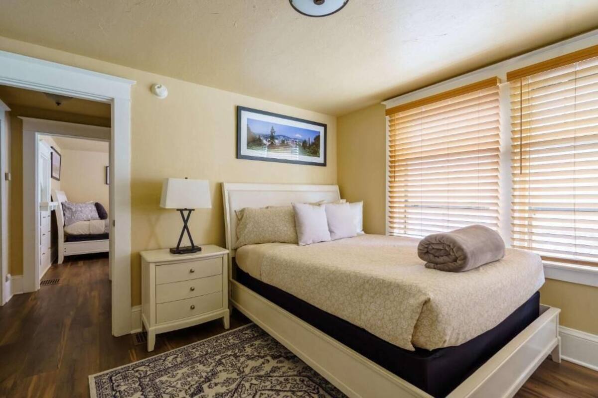 A bedroom with a bed, bedside table, lamp, and a framed picture on the wall.