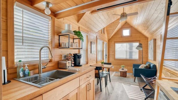 Interior de una cabaña de madera con cocina, comedor y un rincón de descanso acogedor.