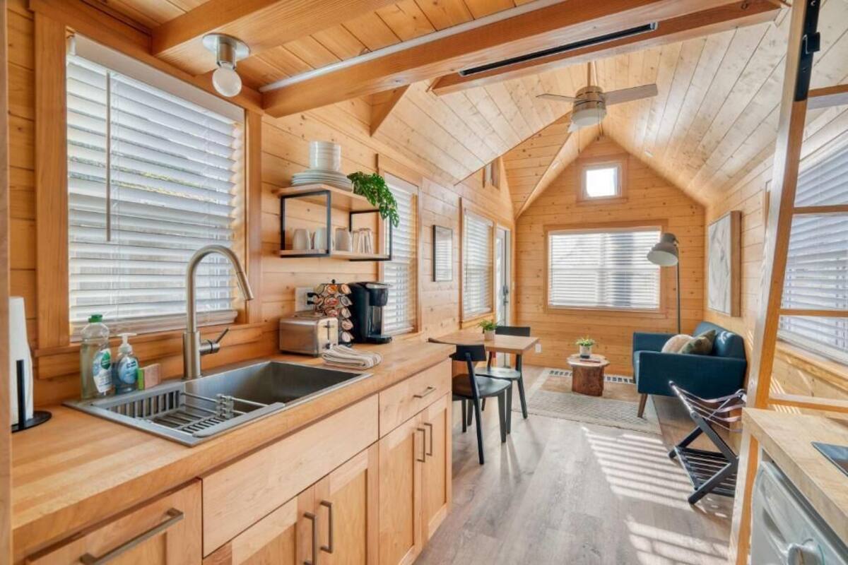 A wooden cabin interior with a kitchen, dining area, and a cozy seating space.