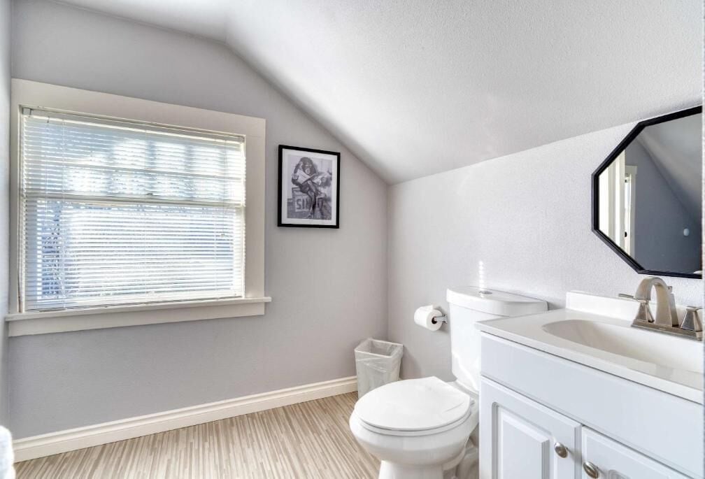 A bathroom with a toilet, sink, and window with blinds.