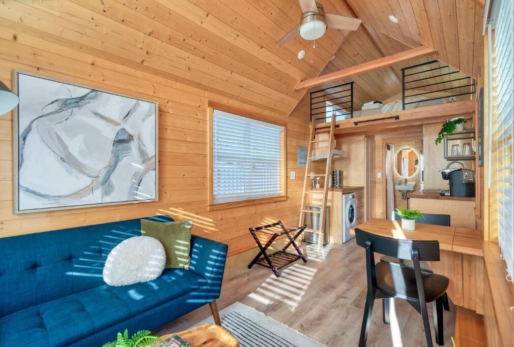 A wooden interior with a sofa, a dining table, and a kitchen area.