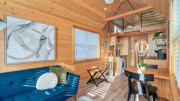 A wooden interior with a sofa, a dining table, and a kitchen area.