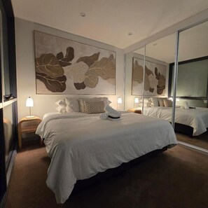 Una habitació d'hotel amb un llit gran, una vetusta, un mirall i una obra d'art penjada a la paret.