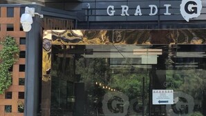 A modern building entrance with a glass door, a sign above reading 'GRADI,' and a security camera on the left. - Charming 2-bedroom Apartment in Central Melbourne (Melbourne)