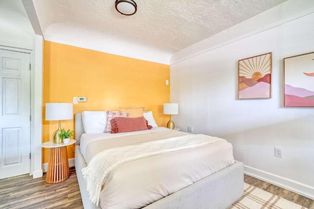 A bedroom with a bed, bedside tables, a wall-mounted lamp, and a door.